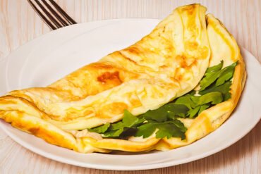 Omletă cu brânză și pătrunjel pe farfurie.