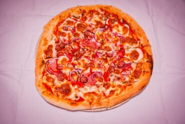 Pizza cu pepperoni și ardei pe masă.