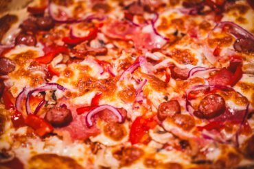 Pizza cu salam și ceapă roșie.